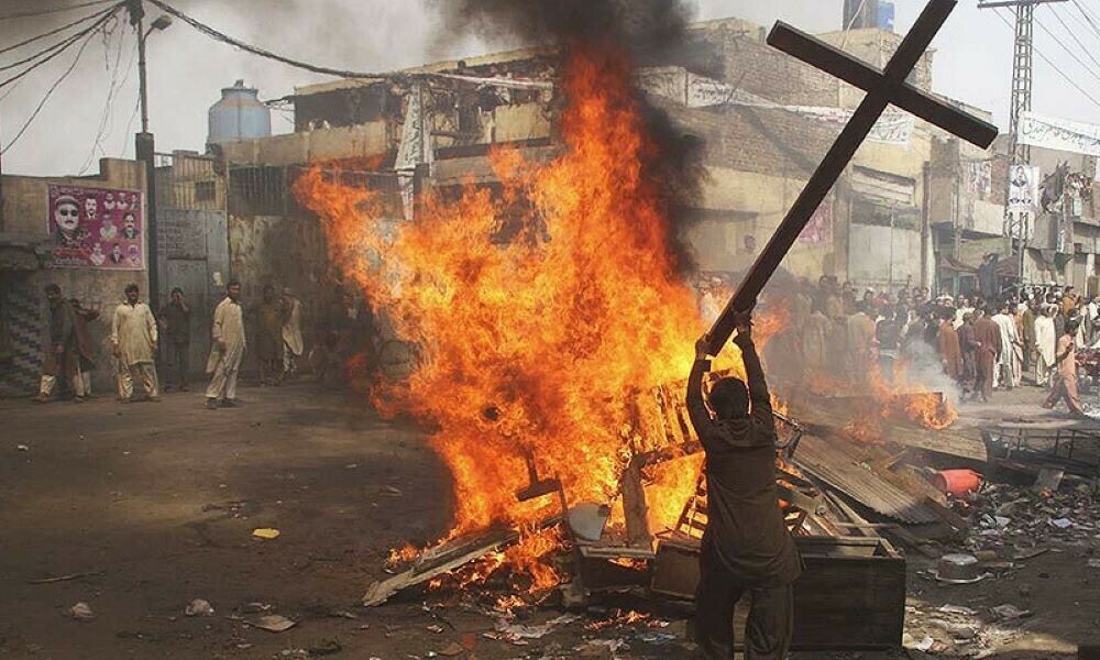Rioters standing near a bonfire containing a wooden cross during the 2013 Joseph Colony mob attack in Lahore.