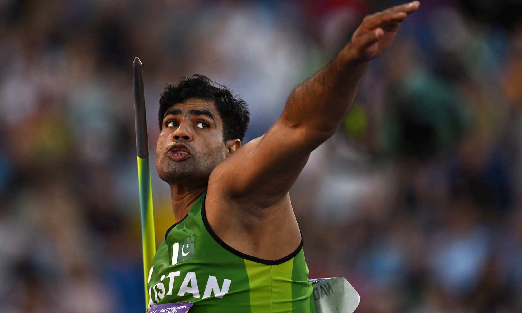 Pakistani athlete Arshad Nadeem wearing a green Pakistan kit as he prepares to release the javelin during the men's javelin throw final.