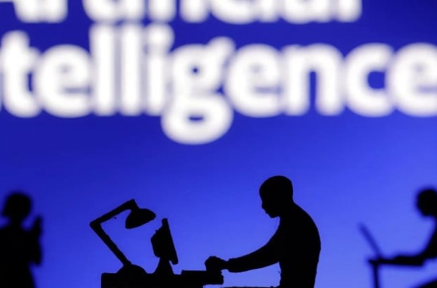 Silhouette of a professional working on a laptop at a desk with an Artificial Intelligence screen display in the background.