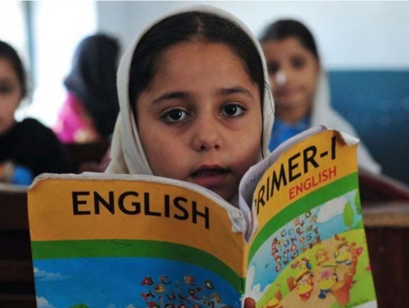 Pakistani primary school students sitting in a classroom listening to their teacher.